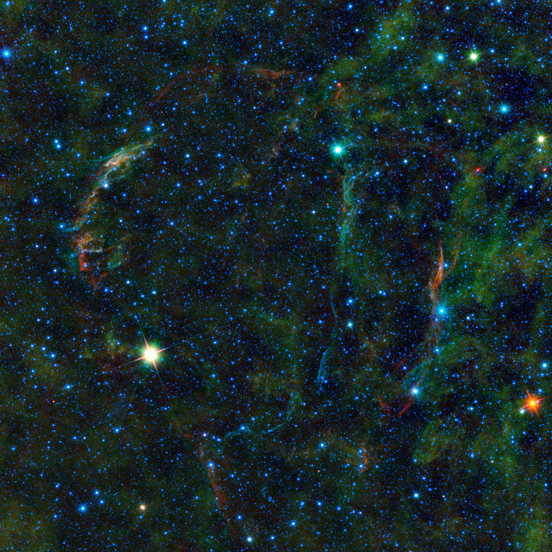 A starfield with many small, blue stars and a few larger, brighter stars, and green wisps.