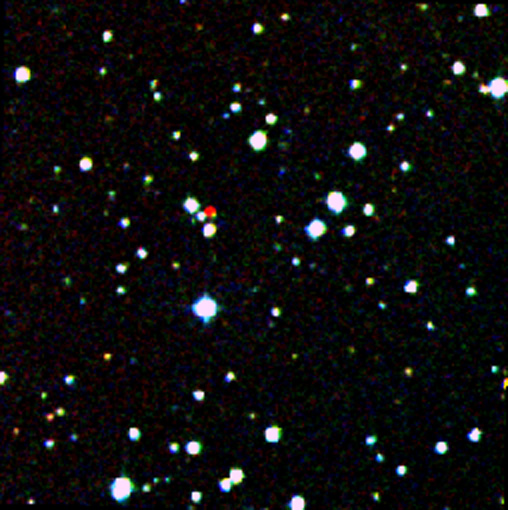 A field of stars in space, mostly blue-white, with a red star near center.