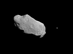 Image shows a grey rock, which is the asteroid, in a black environment, which is space.